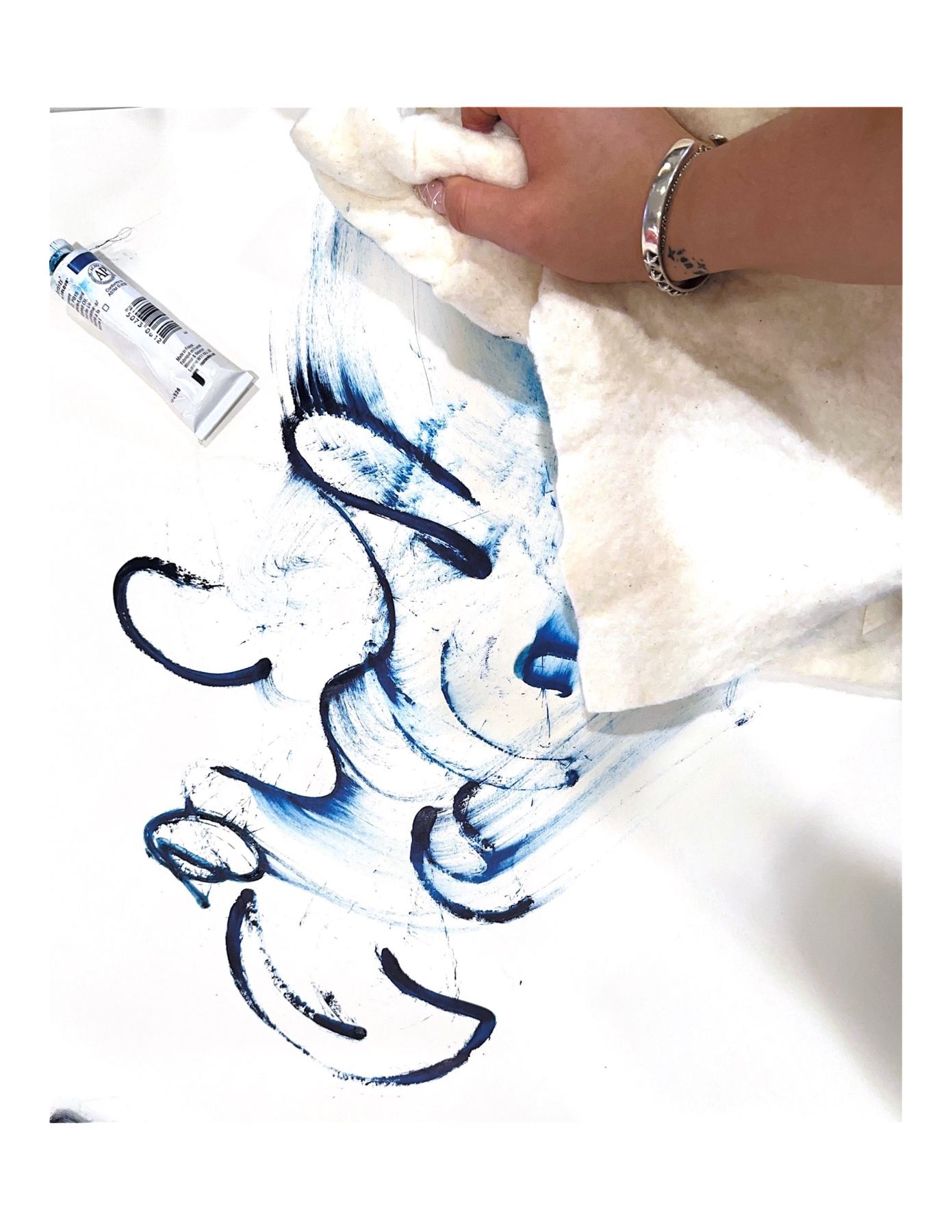 A hand wiping blue ink across fabric