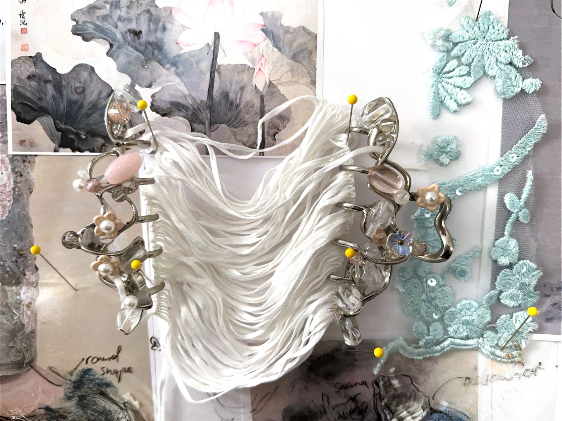 Page from Embellishment Explorations: draped white fabric with ornaments pinned to a collage